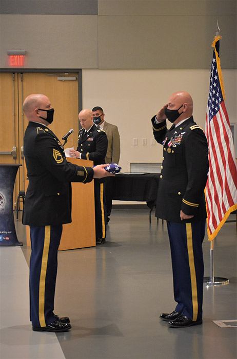 Army Maj. Dana B. Love, Jr. receives an American flag from Army Sgt. 1st Class Daniel P. McGarrah